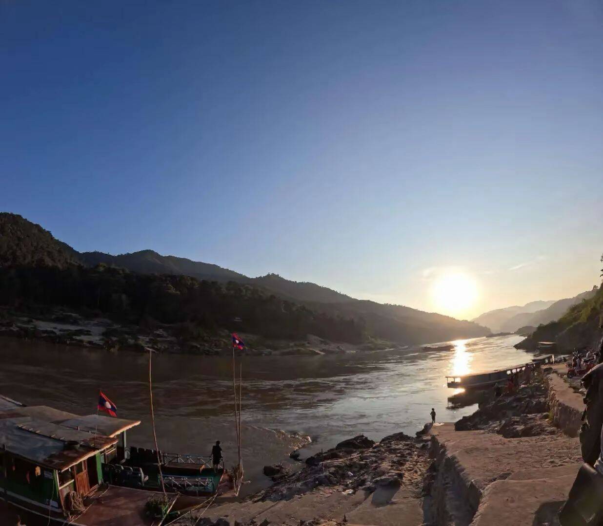Sunset over the Mekong with boats at a rocky landing